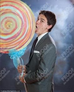 a man in a suit holding a giant lollipop