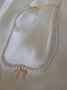 Add a touch of quirky sophistication to your outfit with this pearl chain bow charm necklace. The chain, embellished with pearls, elegantly highlights a charming bow pendant, achieving the perfect blend of style and subtlety. Product Details: length: 16" charm: 1" x 1" bow ext: 3" Ball Chain Ext clasp: Lobster Claw metal finish: Gold Plated anti-tarnish: Double E-coating Coquette Diy, Necklaces Pearl, Bow Pendant, Pearl Necklace Designs, Pearl Chain, Clothing Ideas, Ball Chain, Necklace Designs, Lobster Claw