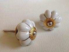 two white flower shaped knobs with gold accents