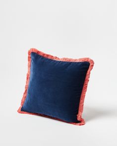 a blue and orange pillow on a white background with an orange fringe trim around the edge