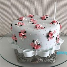 a white cake with pink flowers on it sitting on top of a glass platter