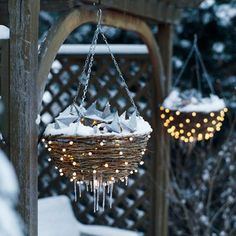 a bird feeder with lights hanging from it's sides and snow on the ground