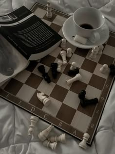 a chess board with black and white pieces next to a cup of coffee on it