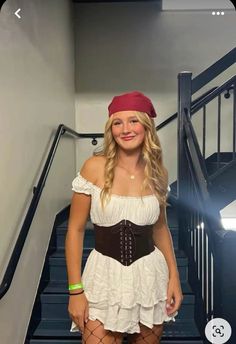 a woman in a white dress and red bandana posing for a photo on the stairs