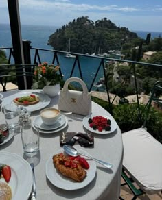 the table is set with food and drinks overlooking the water in front of an island