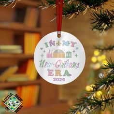 a personalized ornament hanging from a christmas tree in front of a bookshelf