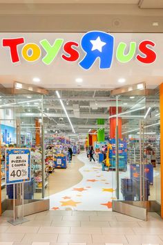 toys r us store front entrance with children's toys on the floor and people walking inside