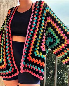 a woman wearing black shorts and a colorful crochet sweater