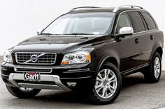 a black volvo suv parked in front of a white wall