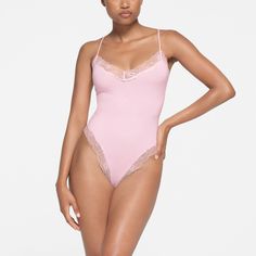 Buy from $64.00: The sexiest way to wear cotton. Made with an elevated version of our signature cotton, this soft and stretchy bodysuit enhances your curves with its fitted, flattering silhouette. Inspired by vintage lingerie, the delicate lace along the triangle neck, underarms, and leg openings makes this style extra sweet. Features a crochet lace SKIMS logo at the center front, adjustable straps, and thong back with a 100% cotton gusset. Fits true to size. | SKIMS Cami Bodysuit | Pink | ... Terry Cloth Romper, Spaghetti Strap Bodysuit, Battenburg Lace, Cami Bodysuit, Full Body Suit, Velvet Bodysuit, V Neck Bodysuit, The Triangle, Sleeveless Bodysuit