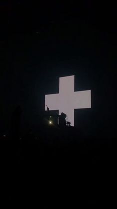 a large white cross on top of a building in the dark