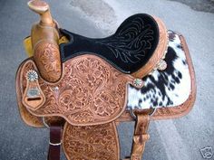 a brown and black horse saddle sitting on the side of a road next to a bottle