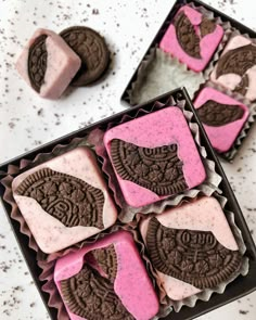 some cookies and ice cream are in a box on a table with pink frosting