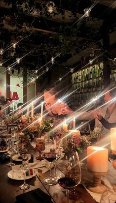 a long table is set with candles and flowers in front of the woman at the bar