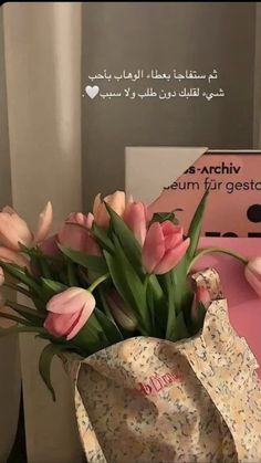 a bouquet of tulips in a vase on a table next to a pink box