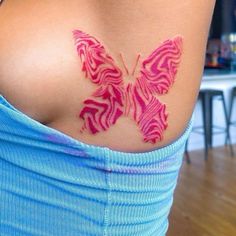 a woman's back with a pink butterfly tattoo on her left shoulder and chest