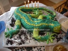 a birthday cake that looks like a green lizard with candles on it's head