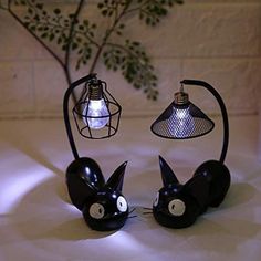 two black cats are sitting next to each other with light bulbs on their heads and eyes