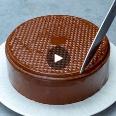 a chocolate cake sitting on top of a white plate with a knife sticking out of it