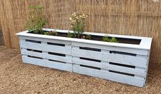 a wooden planter filled with plants next to a bamboo fence