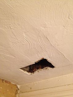 a hole in the ceiling that has been painted with white paint and is being repaired