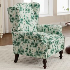 a green chair sitting on top of a rug in front of a white table and window