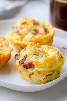 three breakfast muffins on a white plate with a cup of coffee in the background