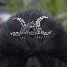 a close up of a person wearing a hair comb with two moon and star designs on it