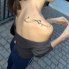 a woman with a small tattoo on her back shoulder and hand holding something in the other hand