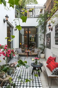 an outdoor living area with black and white checkered tile flooring, potted plants and chairs