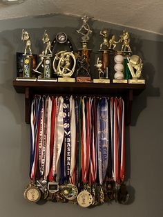 a shelf filled with medals and trophies on top of a wall