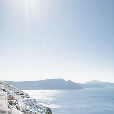 the sun shines brightly over an ocean side town with cars parked on the street