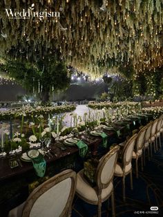 a long table is set up with white flowers and greenery hanging from the ceiling