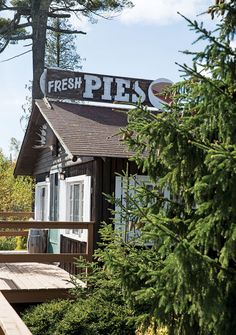 there is a sign that says fresh pies on top of a building in the woods