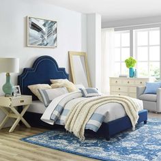 a bedroom with blue and white bedding, rugs and furniture in the room