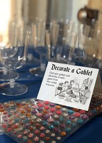 there are many wine glasses on the table and one has a sign that says decorate a goblet