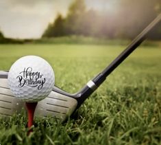 a happy birthday golf ball sitting on top of a tee next to a golf club