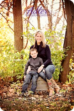 a mother and her son sitting on a bench in the woods for their family portrait