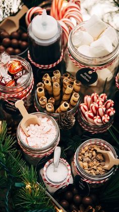 an assortment of candy and candies in glass jars on a table with christmas decorations