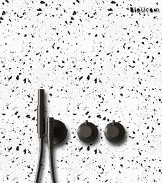 two black knobs on a white wall with speckled paint splattered in the background