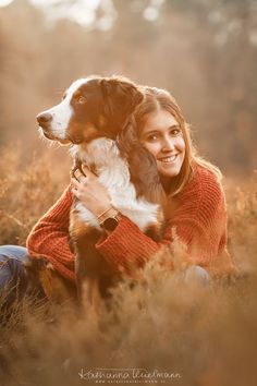 a woman sitting in the grass with her dog