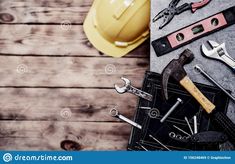 tools and construction equipment laid out on top of a wooden table, including hard hats