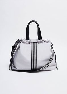 a white handbag with black stripes on the side and shoulder strap, sitting against a white background