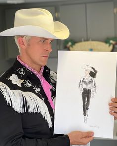 a man in a cowboy hat holding up a drawing