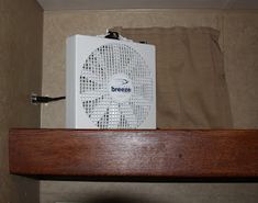 an air conditioner sitting on top of a wooden shelf