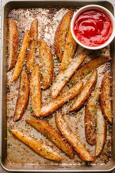 baked potato wedges on a baking sheet with ketchup