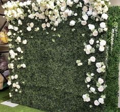 white flowers and greenery are arranged on the wall