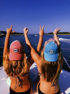 two women on a boat with their arms in the air