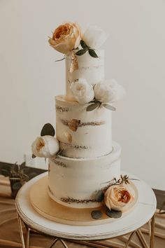 a three tiered wedding cake with flowers on the top and bottom, sitting on a table