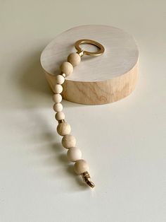 a wooden beaded necklace on a white surface next to a round box with a gold ring